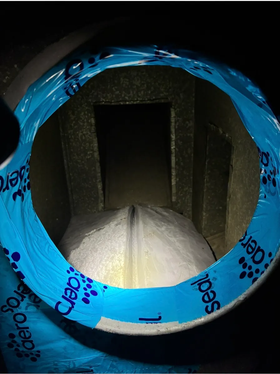 View into a sheet-metal duct opening through a blue Aeroseal-branded connection sleeve